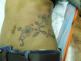 Tatuaje de unas flores por el costado de una mujer