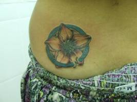 Tatuaje de una flor dentro de un circulo que marca el Norte