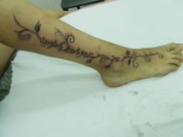 Tatuaje de una enredadera con palabras árabes