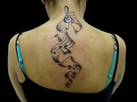 Tatuaje de pentagrama con notas musicales por la espalda