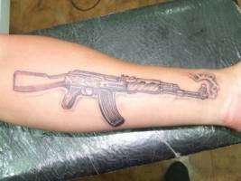 Tatuaje de una ametralladora en el brazo recien disparada