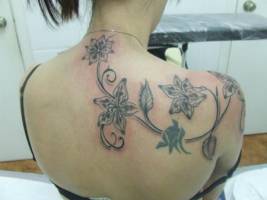 Tatuajes de unas flores en la espalda de una mujer