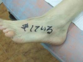 Tatuaje de unas letras orientales en el pie