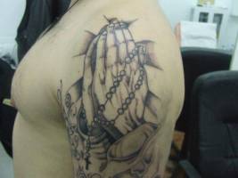 Tatuaje de unas manos con un rosario rezando