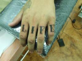 Tatuaje de la palabra LIFE en los dedos