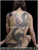 Tatuajes de un dragon con unos kanjis en la espalda de una mujer