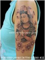 Tatuaje de una diosa en el brazo entre flores