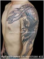 Tatuaje de un ave fénix en el brazo con las plumas de la cola encima del pecho