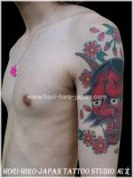 Tatuaje de un ogro japonés en el brazo con algunas flores