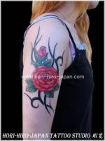 Tatuaje para mujer de rosa en el brazo con tribal