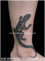 Tatuaje de un lagarto subiendo por el tobillo 
