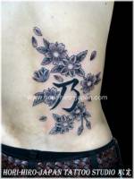 Tattoo de kanji entre flores en la espalda.
