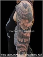 Tatuaje de un dragón entre enroscándose por el brazo de una mujer entre nubes