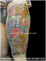 Tatuaje de León Fu entre flores, bajando por la pierna