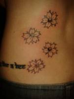 Tatuajes de pequeñas flores en la espalda de una mujer