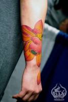 Tatuaje de una flor en la muñeca con un pétalo que cae a la mano