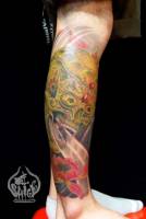 Tatuaje de una calavera entre viento y una flor. Tatuaje en la pierna