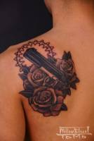 Tatuaje de pistola entre rosas.