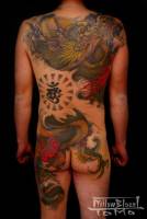 Tatuaje de un dragón en la espalda pasando debajo de una ola