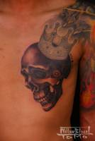 Tatuaje de calavera con corona en el pecho.