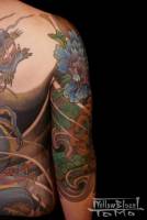 Tatuaje japonés parte de atras del brazo con algunas flores.