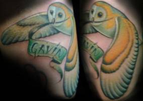 Tatuaje de una lechuza con un nombre entre las alas