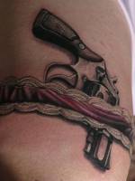 Tatuaje de una pistola guardada en el liguero