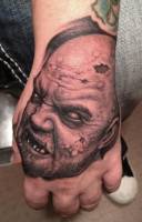 Tatuaje de una cabeza de zombie en la mano