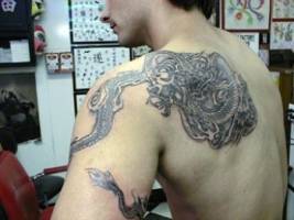 Tatuaje de un dragon donde la cola llega hasta el brazo