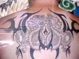 Tatuaje de unos dragones entre tribales para la espalda