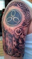 Tatuaje en el brazo de un simbolo celta con casas debajo