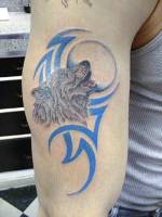 Tatuaje de Lobo aullando a la luna con tribal de fondo