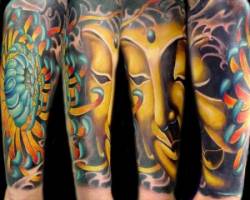 Tatuaje de una flor de loto y la cara de buddha en el brazo
