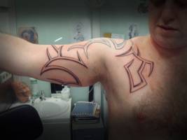 Tatuaje de un tribal en pecho y brazo