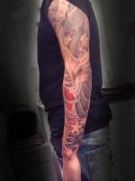 Tatuajes de una carpa con olas en el brazo