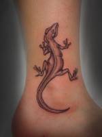 Tatuaje de un lagarto subiendo por el tobillo
