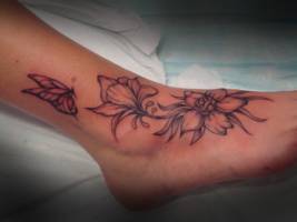 Tatuaje de unas flores en el pie y unas mariposas