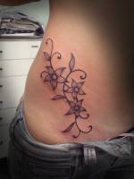 Tatuaje de 3 flores en la cadera de una mujer