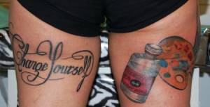 Tatuaje de una frase y una paleta de pintura en las piernas