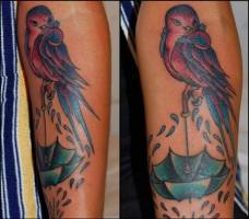 Tatuaje de un pájaro encima de un paraguas