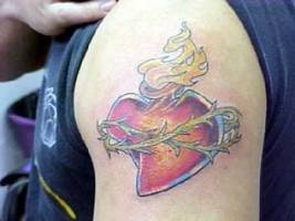 Tatuaje del sagrado corazón, un corazón con fuego dentro y atado con espinos