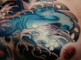 Tatuaje de un tiburón martillo entre olas