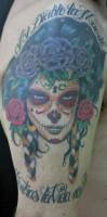 Tatuaje de una chica pintada de calavera mexicana con una frase encima