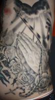 Tatuaje de un ancla y unas manos rezando bajo una luz celestial