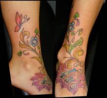 Tatuaje de flores y mariposas con un nombre en el pie