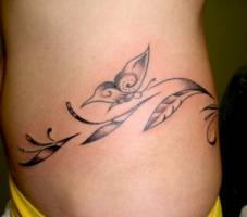 Tattoo de plantas y mariposas en la cadera