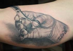 Tatuaje de una mano con unas tijeras