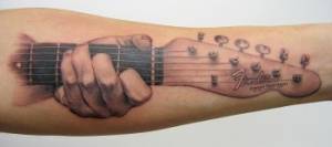 Tatuaje de una mano agarrando una guitarra