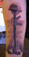 Tatuaje de un casco apoyado en un rifle