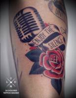Tatuaje de un micrófono y una rosa con una etiqueta